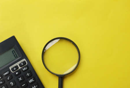 top view and flat lay black magnifying glass and calculator on yellow background.Business and finance conceptの写真素材