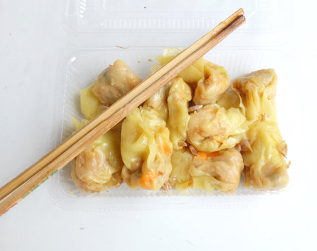 Appetizing a Siu Mai, Shumai, Chinese steamed dumplings, dim sum in a 
In a clear plastic box container with soy sauce, isolated on a white backdropの写真素材
