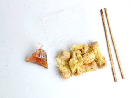 Appetizing a Siu Mai, Shumai, Chinese steamed dumplings, dim sum in a 
In a clear plastic box container with soy sauce, isolated on a white backdropの写真素材