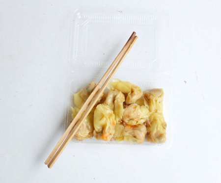 Appetizing a Siu Mai, Shumai, Chinese steamed dumplings, dim sum in a 
In a clear plastic box container with soy sauce, isolated on a white backdropの写真素材