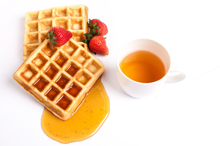 a cup of tea serve with waffles, syrup and strawberryの写真素材