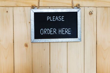 Order here sign hanging on wooden backgroundの写真素材