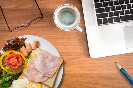 work with breakfast - coffee, laptop and breakfast set - concept of working and eatingの写真素材