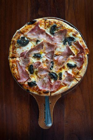 traditional italian pizza with ham and mushrooms on wooden tableの写真素材