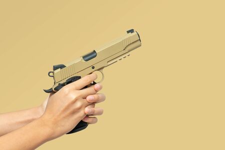 desert color pistol in hand ready to shoot on target isolated on brown background with copy spaceの写真素材