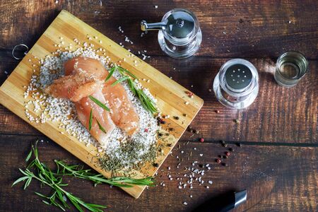Chicken jerky lies on a board with spices and sea salt. Rosemary, cardamom, pepper.の写真素材