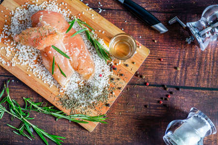 Chicken jerky lies on a board with spices and sea salt. Rosemary, cardamom, pepper.の写真素材