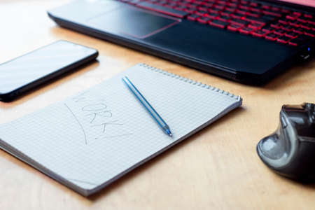 On the table near the laptop is a notebook in which the word work is written. Top view layout of a daily work planの写真素材