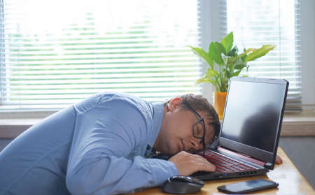 Tired of hard work student guy sleeping on laptop at table