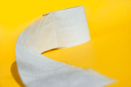 Rolls of new toilet paper lie on a yellow background