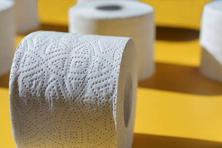 Rolls of new toilet paper lie on a yellow background