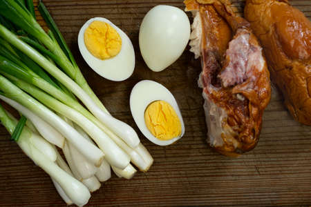 Boiled eggs, fresh chives and smoked chicken laid out on a boardの写真素材