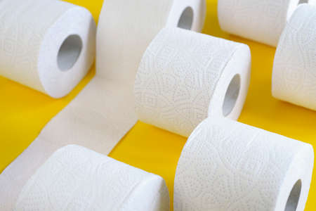 Rolls of new toilet paper lie on a yellow backgroundの写真素材