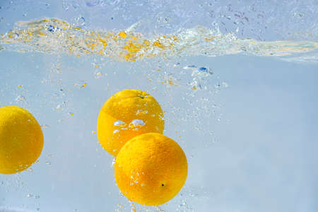 oranges fall into the water with bubbles