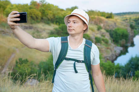 guy takes a selfie while traveling through the canyon. Guy with a backpack and a blue t-shirt