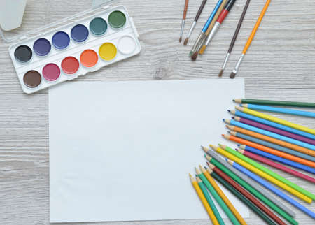 Tools for drawing, stationery, artist's workplace. Paint and pencils and blank paper on wooden table, top view, flat lay, copy space. school drawing suppliesの写真素材