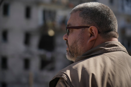 Portrait of a man who looks at his destroyed house, which was hit by a shell from military...