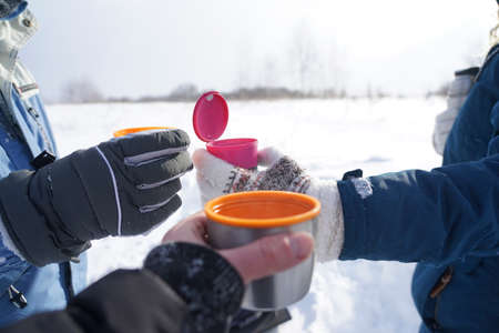 Three hands hold thermo mugs with coffee