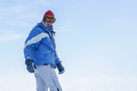Snowboarder stands on the slopes of the mountain with a snowboard in ski equipment