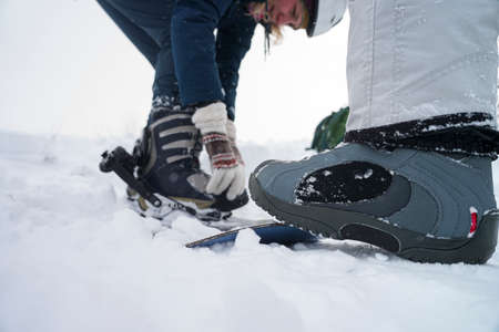Foot in a boot holds a snowboard on a slope