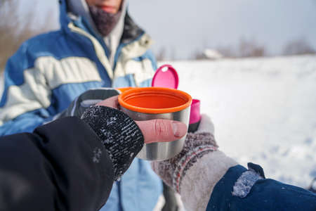 Three hands hold thermo mugs with coffeeの写真素材