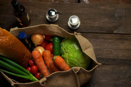 eco bag made from natural burlap with food and vegetables stands on a wooden table. Eco concept.の写真素材