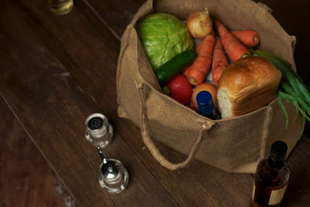 eco bag made from natural burlap with food and vegetables stands on a wooden table. Eco concept.の写真素材