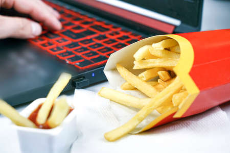 fast food lies near a laptop computer, fries and burger