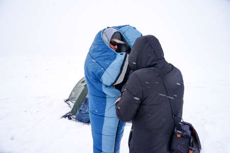 Portrait of a guy in a sleeping bag during the winter expedition.