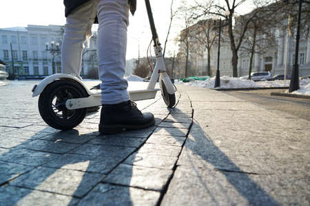 Electric scooter close-up. The guy stands near the electric scooter in the park. beautiful photo of...