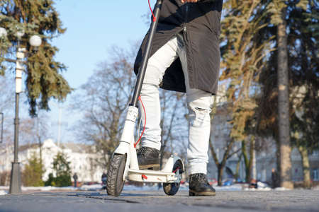 The guy stands with one foot on an electric scooterの写真素材