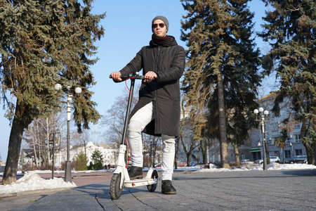 The guy stands with one foot on an electric scooterの写真素材
