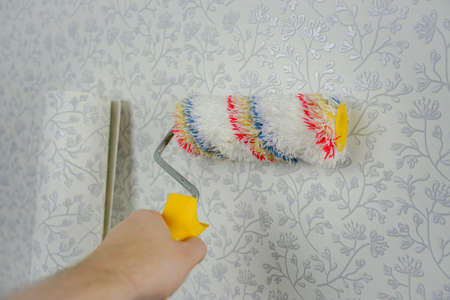 Hand holds a roller for painting the walls. Soft roller for wallpapering and textured applicationの写真素材