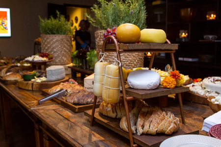 Homemade breads and assorted cheeses exposed on the wooden table.の写真素材