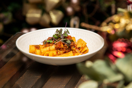Rigatoni pasta with sugo sauce and lamb ragout, with coriander leaves on top. Christmas background.の写真素材