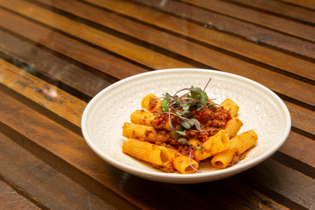 Rigatoni pasta with sugo sauce and lamb ragout, with coriander leaves on top.の写真素材