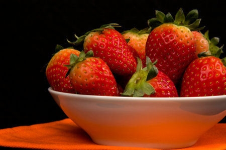 Red fresh strawberry in a bowl on black backgroundの写真素材