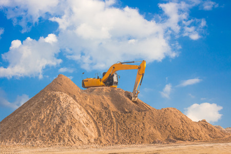 Excavators work on soil piles for construction.