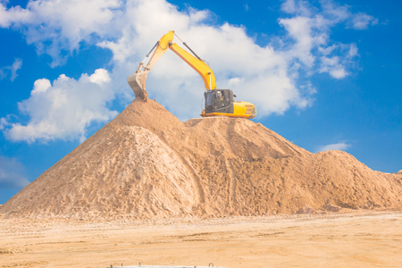 Excavators work on soil piles for construction.の写真素材