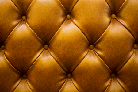 The brown soft leatherette background with asymmetrical buttons. Soft and expensive furniture elements. Luxury backgroundの写真素材