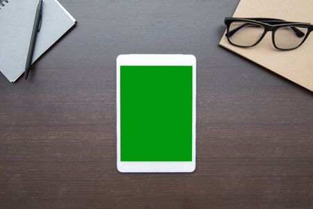 Work space desk table top overhead place tablet green screen at center layout left right have notebook glasses and penの写真素材
