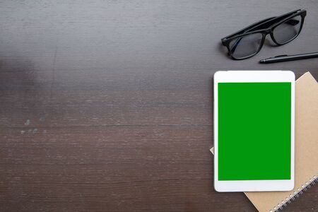 Desk table top overhead place layout right have tablet green screen for inscert advertising product on notebookの写真素材