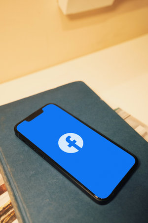 October 3, 2022: Facebook logo on smartphone screen. Smartphone on a book.のeditorial素材