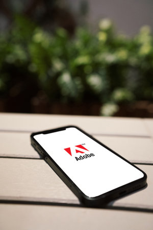 October 6, 2022: Adobe logo on smartphone screen. Smart phone on a tableのeditorial素材