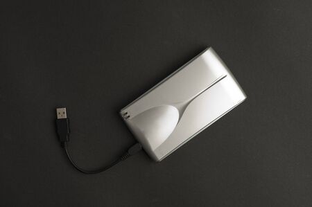 Aluminum external hard drive with connection cable (USB), black background Top viewの写真素材