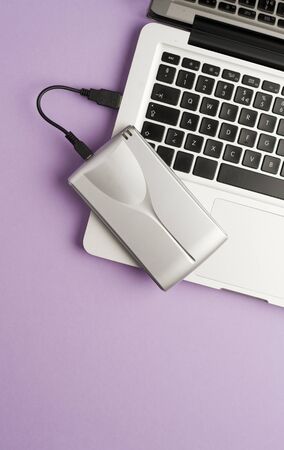 aluminum external hard drive, above laptop, purple background.concept office.top viewの写真素材