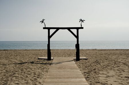 beach landscape, with path and wooden arch, blue sky background sea, space to writeの写真素材