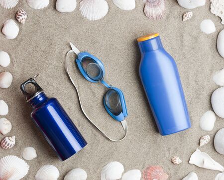 Beach set, water bottle, glasses, and sunscreen, shells and stonesの写真素材