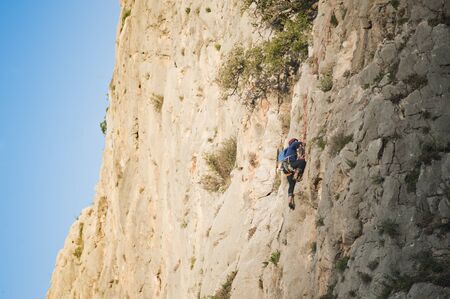 Rock wall climber climbing at sunrise, space to write.の写真素材