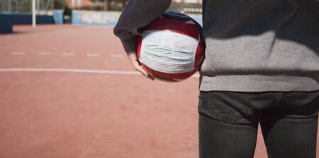 covip-19, young boy with soccer ball, with respiratory mask soccer field without children